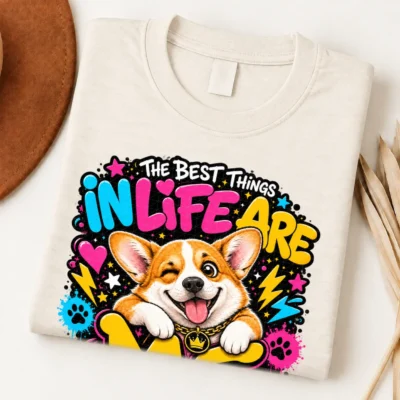 corgi pride shirt artwork with a winking orange-and-white corgi, tongue out, crown medallion, neon lettering, hearts, lightning bolts, and paw prints.