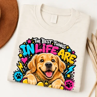 Golden Retriever pride shirt artwork with a smiling golden dog, tongue out, crown medallion, bold neon lettering, hearts, paw prints, and lightning bolts.