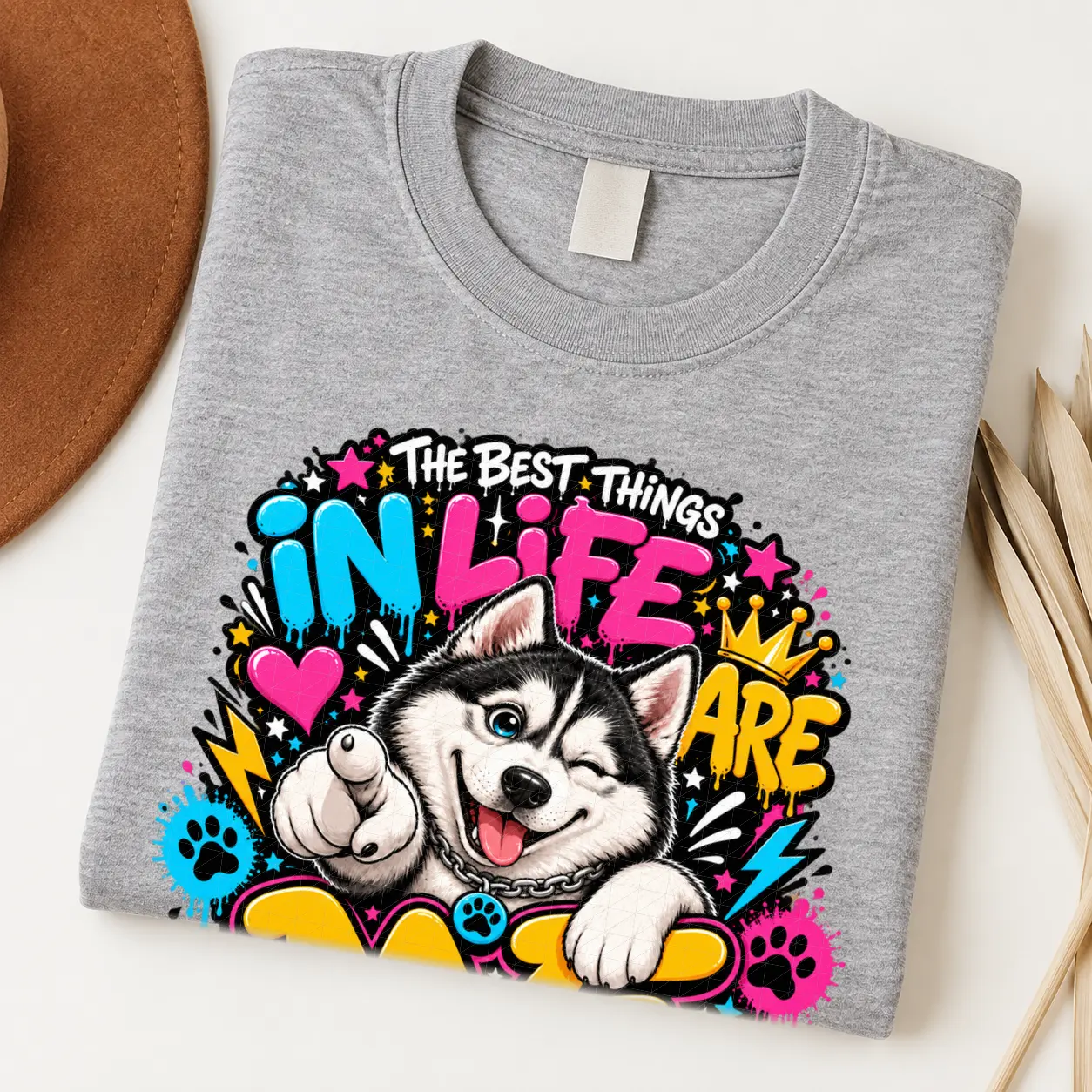 Husky pride shirt artwork with a winking black-and-white Husky, pointing paw, blue eye, crown medallion, neon lettering, bolts, hearts, and paw prints.
